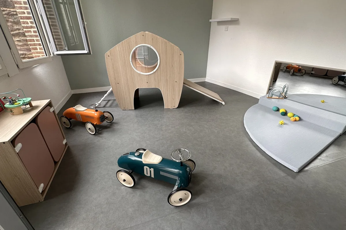 Salle de motricité de la micro-crèche My Little Crèche Rennes Thabor : voitures à pédales, maisonnette et toboggan